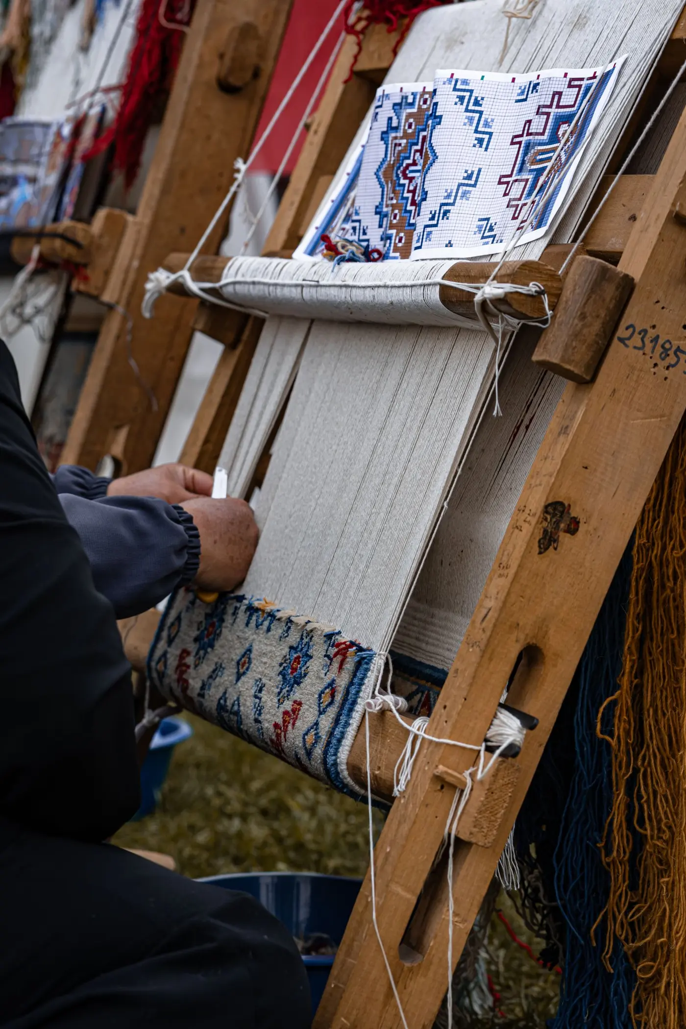 Artisan’s hands weaving a traditional rug on a wooden loom